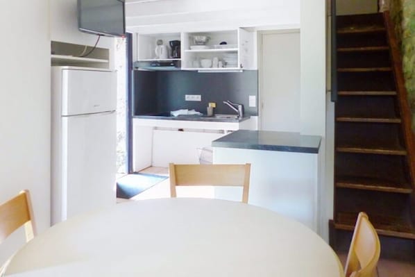 Une cuisine compacte comprenant un coin repas, un réfrigérateur et un escalier menant à un niveau supérieur.