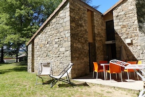 Un edificio de piedra con un pequeño patio y mobiliario exterior.
