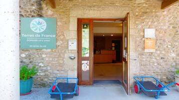 A stone building entrance with a sign for 'Terres de France Domaine des Vans' and a contact number.