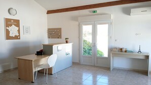 Een kamer met een bureau, stoel en een deur naar buiten.