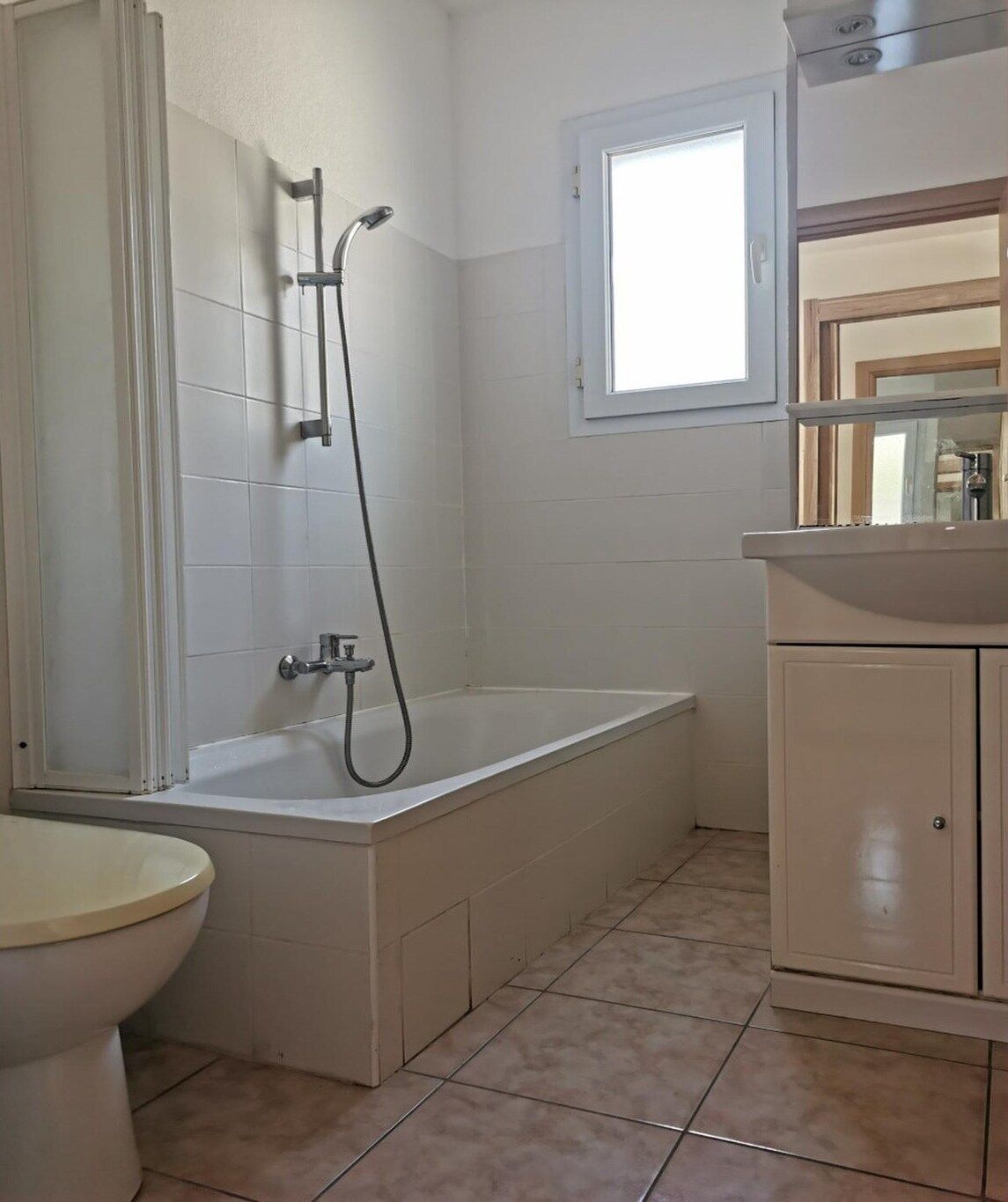 A bathroom with a bathtub, toilet, and a window.
