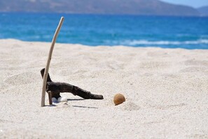 Una spiaggia con una struttura in legno, un bastone e una palla sulla sabbia.