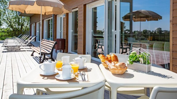 A sunlit outdoor dining area with tables, chairs, and umbrellas. - Couple Stay Near Mont-Saint-Michel (Roz-sur-Couesnon)
