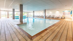 An indoor swimming pool with wooden decking, lounge chairs, and a tiled ceiling. - Couple Stay Near Mont-Saint-Michel (Roz-sur-Couesnon)