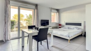 Une chambre d’hôtel moderne équipée d’un lit, d’un bureau avec une chaise, d’une télévision et de grandes fenêtres.