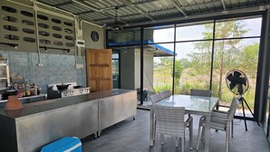 Una cocina moderna con una isla grande, un comedor con sillas de mimbre y vistas a zonas verdes.