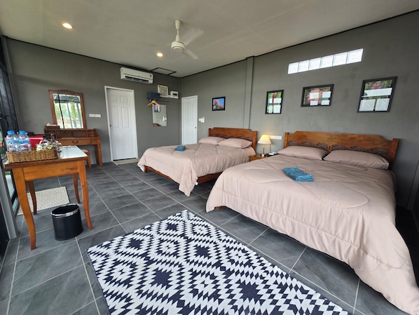 A hotel room with two beds, a desk, a chair, a trash bin, and a patterned rug.