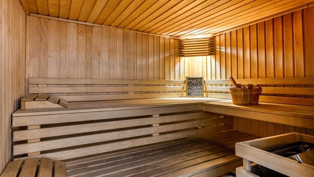 A wooden sauna with benches, a bench with a towel, and a wooden bench with a bucket. - Chic 4-Guest Studio, Wellness & Pool (Argeles-sur-mer)