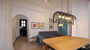 A modern living room with a wooden dining table, a grey sofa, and a unique birdcage light fixture. - Casa al Porto (Zakinthos)