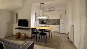 A modern kitchen with a dining area, a flat-screen TV, and a chandelier. - Casa al Porto (Zakinthos)