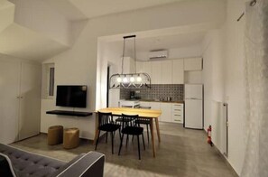 A modern kitchen with a dining area, a flat-screen TV, and a chandelier. - Casa al Porto (Zakinthos)