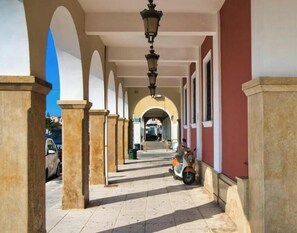 A corridor with arches, a scooter, and a street visible in the background. - Casa al Porto (Zakinthos)
