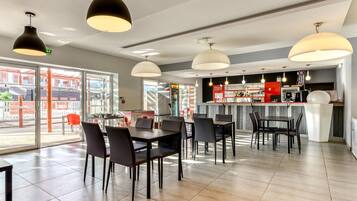 A restaurant with tables and chairs, a bar area, and large windows.