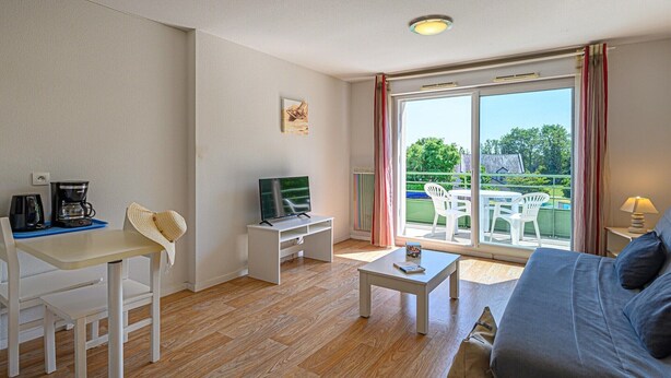 A room with a TV, coffee maker, and a dining table with chairs. - Cozy Apartment Stay Near Vannes (Plescop)