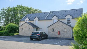 A building with a parking lot and a black car parked in front. - Cozy Apartment Stay Near Vannes (Plescop)