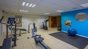 A gym with exercise equipment, a blue wall, and a large exercise ball. - Cozy Apartment Stay Near Vannes (Plescop)