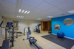 Een sportschool met fitnessapparatuur, een blauwe muur en een grote fitnessbal.