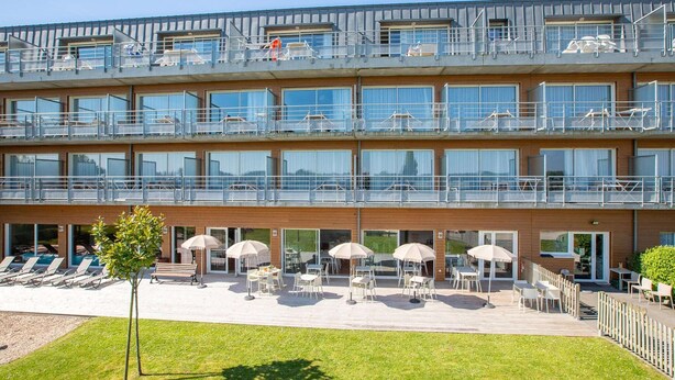 Un hotel de diverses plantes amb terrassa exterior i zona de piscina.