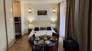 A hotel room with a bed, bedside lamps, a table with breakfast, and a painting on the wall. - 4-persons studio with balcony (BOLQUERE)