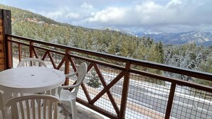 A balcony with a table and chairs, overlooking a snowy landscape with trees and mountains. - Attractive studio in Bolquère (BOLQUERE)