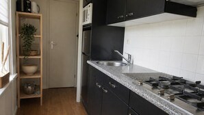 A kitchen with a granite countertop, stainless steel appliances, and a wooden shelf unit. - Vechtdal Chalet de Berk (Rheezerveen)