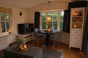 Ein Wohnzimmer mit Fernseher, einem runden Esstisch, Stühlen, einem Kamin und einem Bücherregal.