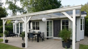 A covered patio with a table and chairs, potted plants, and a white pergola structure. - Vechtdal Chalet de Berk (Rheezerveen)