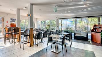A modern dining area with tables and chairs, a sofa, and a bookshelf.