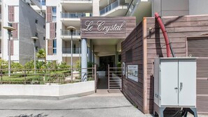 Ein Gebäude mit einem Schild, das 'Le Crystal' zeigt, einem verschlossenen Eingang und einem Technikschrank.