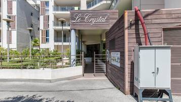 A building with a sign reading 'Le Crystal,' a gated entrance, and a utility box.