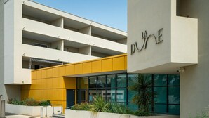 En modern byggnad med en gul fasad, flera balkonger och en skylt med texten ”LA ONE”.