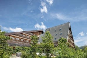A modern building with multiple balconies and a sloped roof, surrounded by greenery. - Cosy Alpine Studio for Romantic Getaway (GRESSE-EN-VERCORS)