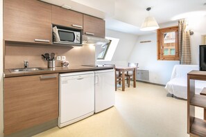 Una cocina compacta equipada con microondas, lavavajillas y un comedor con mesa y sillas.