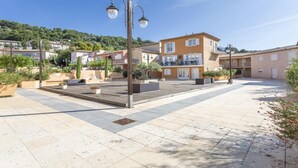 Pátio com piso de azulejos, área de estar externa e um edifício com sacadas.