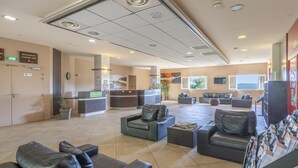 Um lobby de hotel com áreas de estar, um balcão de recepção e um restaurante/bar de lounge.