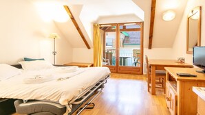 Een hotelkamer met een bed, een bureau, een stoel, een televisie en een balkon met uitzicht.