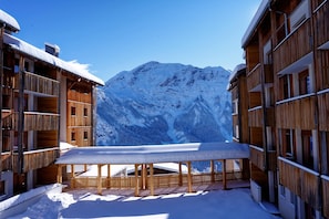 Ein Holzhof mit Balkonen und einem Tisch mit Schnee davor.