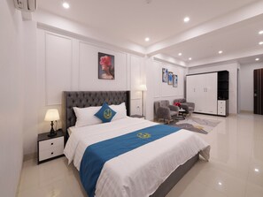 Ein modernes Hotelzimmer mit einem großen Bett, Nachttischlampen, einem Kleiderschrank und einer Sitzecke mit Sesseln.