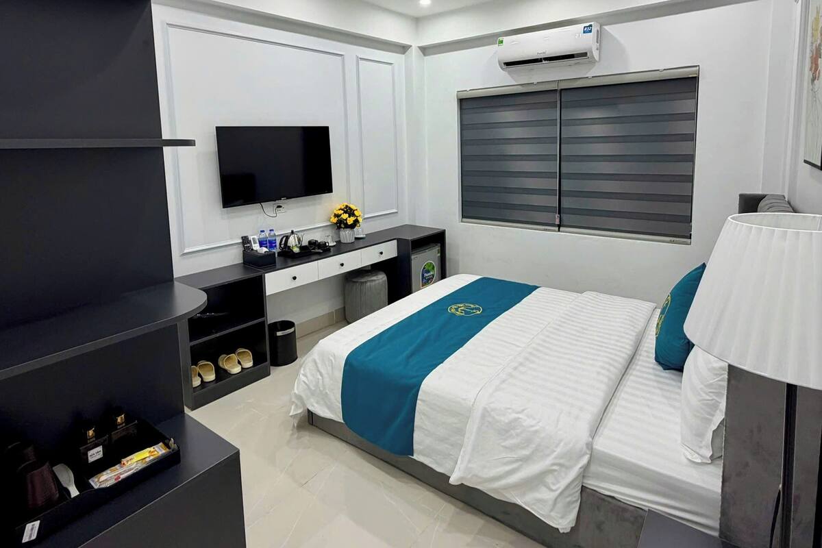 Quarto de hotel moderno com cama, televisão, escrivaninha e ar condicionado.