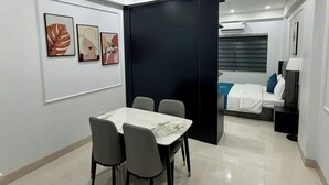 A modern room with a dining table, chairs, a bed, and a small desk. - RUBY 2 HOTEL (Hanoi)