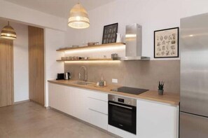 Una cocina moderna con encimera de madera, electrodomésticos de acero inoxidable e iluminación colgante.