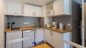 A compact kitchen with white cabinets, a microwave, a coffee maker, a dishwasher, and a small refrigerator. - Central Auris-en-Oisans Stay for 4 (Germ)