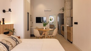 Ein modernes Hotelzimmer mit Bett, Nachttisch, Lampe und Blick auf den Speisesaal.