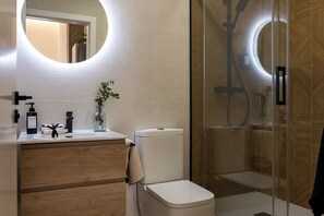 A modern bathroom with a toilet, sink, and shower enclosure. - Almirante Suites B (València)