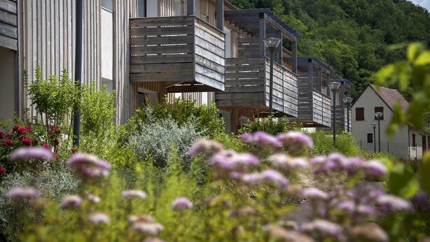 A modern building with a wooden facade, surrounded by lush greenery and flowers. - Stay Near Prehistoric Sites (LES  EYZIES  DE  TAYAC)