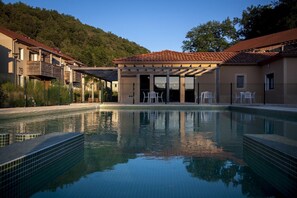 A pool with a tiled edge, a covered seating area, and buildings with balconies. - Stay Near Prehistoric Sites (LES  EYZIES  DE  TAYAC)