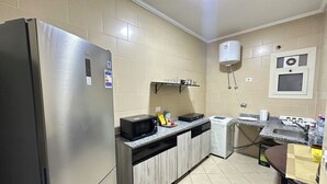 A kitchen with a stainless steel refrigerator, microwave, and a sink with a faucet. - Luxury Stay in Sheikh Zayed -Private Garden + Swimming Pool (6th of October City)