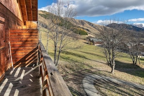 Eine Holzhütte mit einem Balkon mit Blick auf eine gebirgige Landschaft.