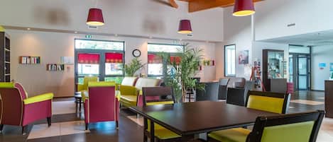 Een modern interieur met een houten plafond, een centrale eettafel, kleurrijke stoelen en potplanten.