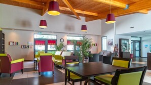 Un intérieur moderne avec un plafond en bois, une table à manger centrale, des chaises colorées et des plantes en pot.